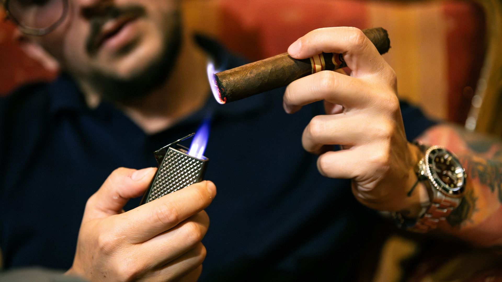 Hand lighting a cigar with a flame from a textured lighter