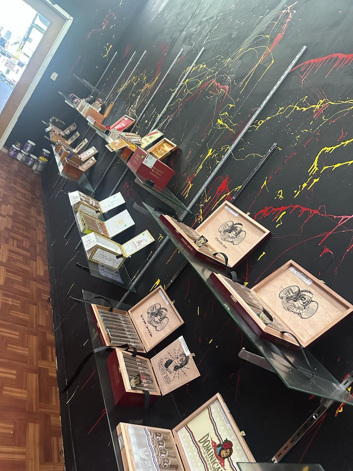 Cigar boxes displayed on black backdrop with colorful paint splatters