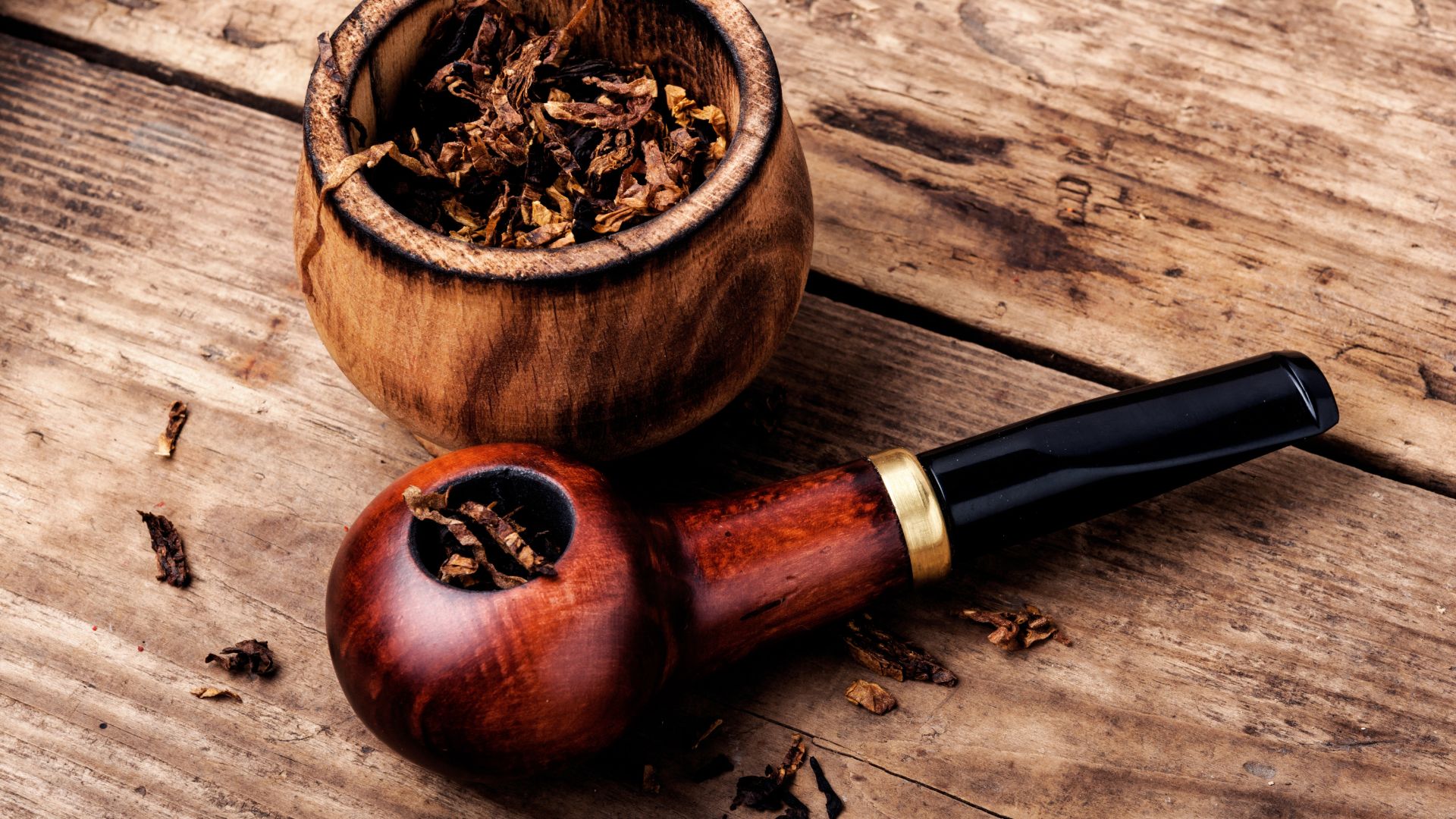 Vintage wooden tobacco pipe and wooden jar with loose tobacco leaves